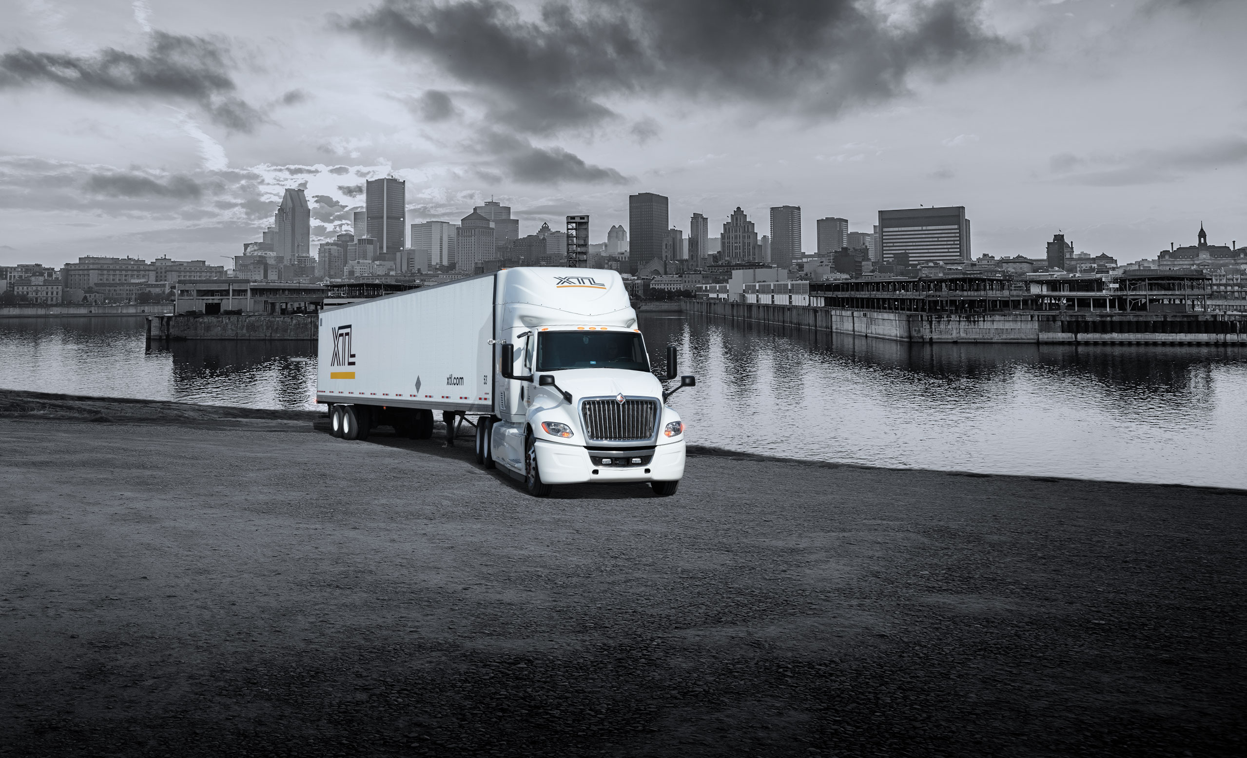 XTL transport truck and trailer parked, with the city of Montreal in the background