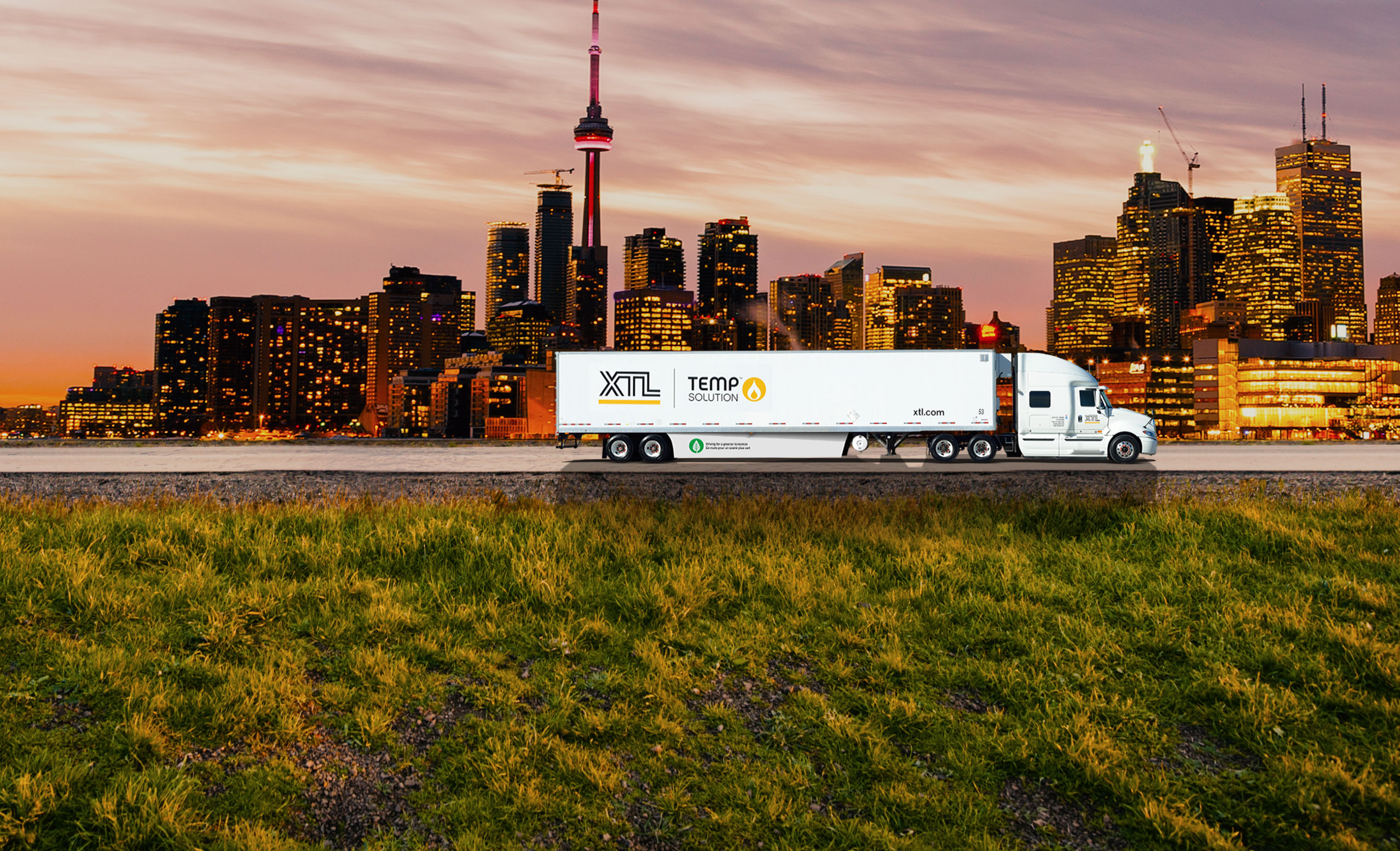 XTL transport truck and trailer driving on road, with city of Toronto in the background