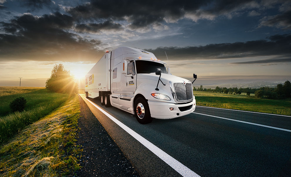 XTL transport truck driving on the highway with picturesque sunset in the background